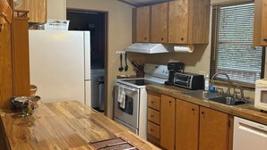 A compact kitchen with wooden cabinets, a built-in oven, a microwave, and a sink. - Cozy Cabin in the Mountains (Newland)