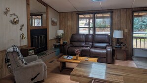 A cozy living room with a fireplace, leather sofa, and a wooden coffee table. - Cozy Cabin in the Mountains (Newland)