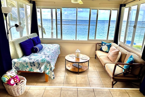 Cottage sitting area with twin bed, surrounded by ocean view on 3 sides.