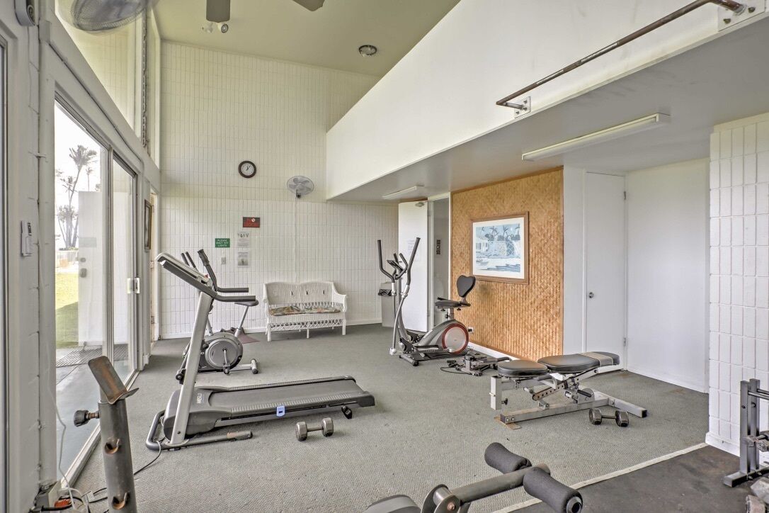 Ett gym med konditionsmaskiner, en bänk och en motionscykel som är monterad på väggen.
