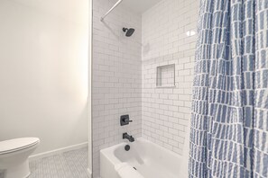 Een bad/douchecombinatie, handdoeken, toiletpapier