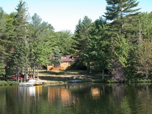 A house by a lake with a boat docked nearby. - Quiet year round lake home, swimming/fishing, near Pictured Rocks, trail access (Shingleton)