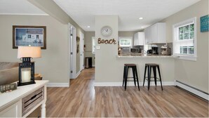 A kitchen with a clock, a bar area, and a wall with the word "Beach". - Tara Cove Cottage (Ogunquit)