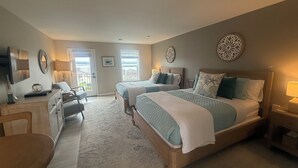 Une chambre avec deux lits, un bureau, une chaise, une commode et une fenêtre donnant sur un beau paysage.