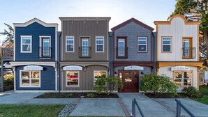Une rangée de maisons de ville à trois étages, toutes dotées d’un porche à l’avant, d’un petit jardin et d’une entrée bien visible.