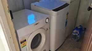 A laundry area with a front-loading washing machine and a stacked washer and dryer. - Womans Beauty  (Christchurch)