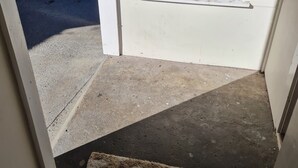 A doorway leading to a patio area with a concrete floor and a rug. - Womans Beauty  (Christchurch)