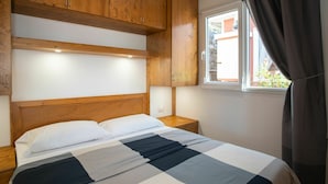 Une chambre à coucher avec une tête de lit en bois, une couvre-lit à carreaux, une table de chevet et une fenêtre avec des rideaux.