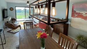 A dining area with a wooden table, chairs, a vase with flowers, and a hanging light fixture. - 3 bedroom condo in cocoa beach (Cocoa Beach)