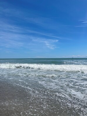 Uma praia com ondas e céu claro.