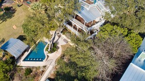 Oversigtsbillede af et stort hus med swimmingpool, flere terrasser og omgivende træer.