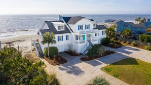 A coastal house with a balcony, a staircase leading to the entrance, and a view of the ocean. - Stay @ Ocean Spray at the Blue Horizon (Sullivan's Island)