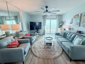 A modern living room with a ceiling fan, two sofas, a TV, and a balcony view.