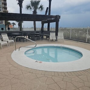 A swimming pool with a wooden deck, lounge chairs, and a pergola. - Gulf Front 2/2 | 20 Ft Balcony | On the Beach (Gulf Shores)