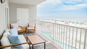 En balkong med utsikt över stranden, en pool och en dörr.