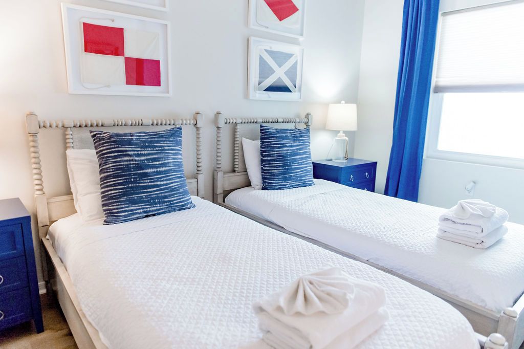 Une chambre d’hôtel avec deux lits, une table de chevet, une lampe et des œuvres d’art accrochées au mur.