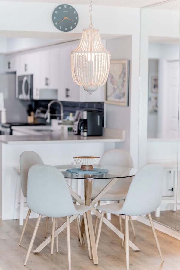 A modern kitchen with a dining area featuring a glass table and wooden chairs.