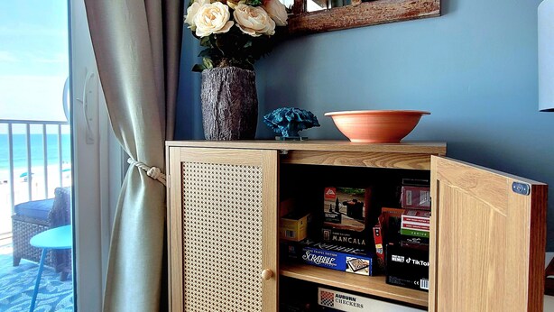 Ett träskåp med en flätad frontpanel, en vas med blommor och en skål ovanpå.