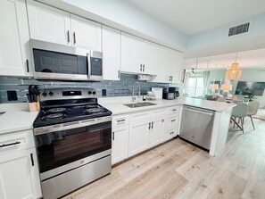 A modern kitchen with white cabinets, a stainless steel stove, and a microwave. - Gulf Front 2/2 | 20 Ft Balcony | On the Beach (Gulf Shores)