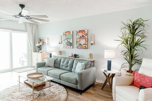 A living room with a sofa, a coffee table, a lamp, a plant, and artwork on the wall.