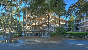 A multi-story hotel with outdoor parking, surrounded by trees and a clear sky. - Ocean front condo with amazing ocean views! (Hilton Head Island)