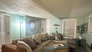 A living room with a sectional sofa, a small table, and a potted plant. - Beautifully remodeled home steps away from the Beach! (Jacksonville Beach)