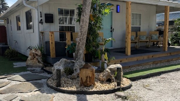 A two-story house with a covered porch, a stone pathway, and a Buddha statue. - Beautifully remodeled home steps away from the Beach! (Jacksonville Beach)