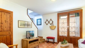 Una stanza accogliente con arredi in legno, una televisione, una panca e una porta con tende.