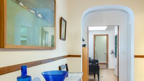 Un corridoio con un grande quadro, un vaso blu e un'immagine incorniciata al muro.