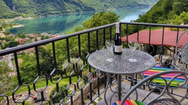 A balcony with a table and chairs, overlooking a lake and mountains. - Casa Pina by Interhome (Porlezza)