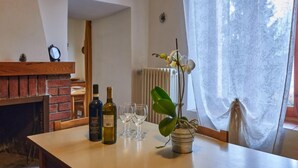 A dining area with a brick fireplace, a table with wine bottles and glasses, and a potted orchid. - Casa Pina by Interhome (Porlezza)