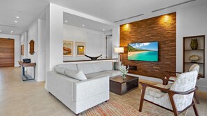 A modern living room with a grey sofa, a coffee table, and a TV mounted on a wooden wall.