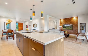 A modern kitchen with a central island, wooden cabinetry, and pendant lighting.