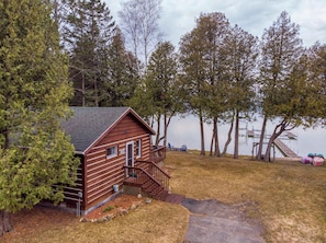 A cabin with a wooden exterior, a porch, and a dock extending into a lake.