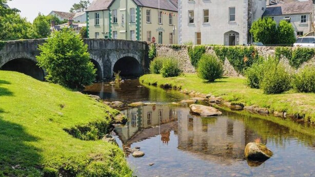 A stone bridge over a calm stream, surrounded by lush greenery and traditional buildings. - Beautiful Apartment in Rostrevor Northern Ireland (Rostrevor)