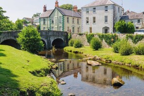 A stone bridge over a calm stream, surrounded by lush greenery and traditional buildings. - Beautiful Apartment in Rostrevor Northern Ireland (Rostrevor)