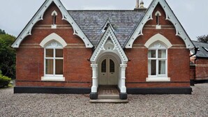 A brick building with a symmetrical facade, two arched windows, and a central entrance with a pointed archway. - Beautiful Apartment in Rostrevor Northern Ireland (Rostrevor)