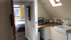 A compact bedroom with a bed, a kitchenette with a toaster, a sink, and a small window. - Beautiful Apartment in Rostrevor Northern Ireland (Rostrevor)