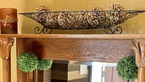 Un meuble en bois doté d’étagères en verre, de pommes de pin décoratives et de petites plantes en pot.