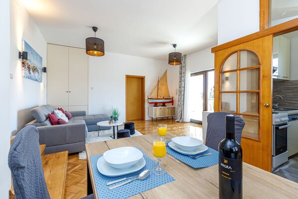 A modern living room with a dining area, a sailboat model, and a kitchen visible through an open door. - Exclusive Pool Escape Near Sea, Krk, Croatia (Krk)