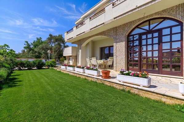 A modern house with a well-maintained lawn, outdoor furniture, and a large arched window. - Exclusive Pool Escape Near Sea, Krk, Croatia (Krk)