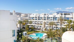 Un hotel con piscina, palmeras y una montaña al fondo.