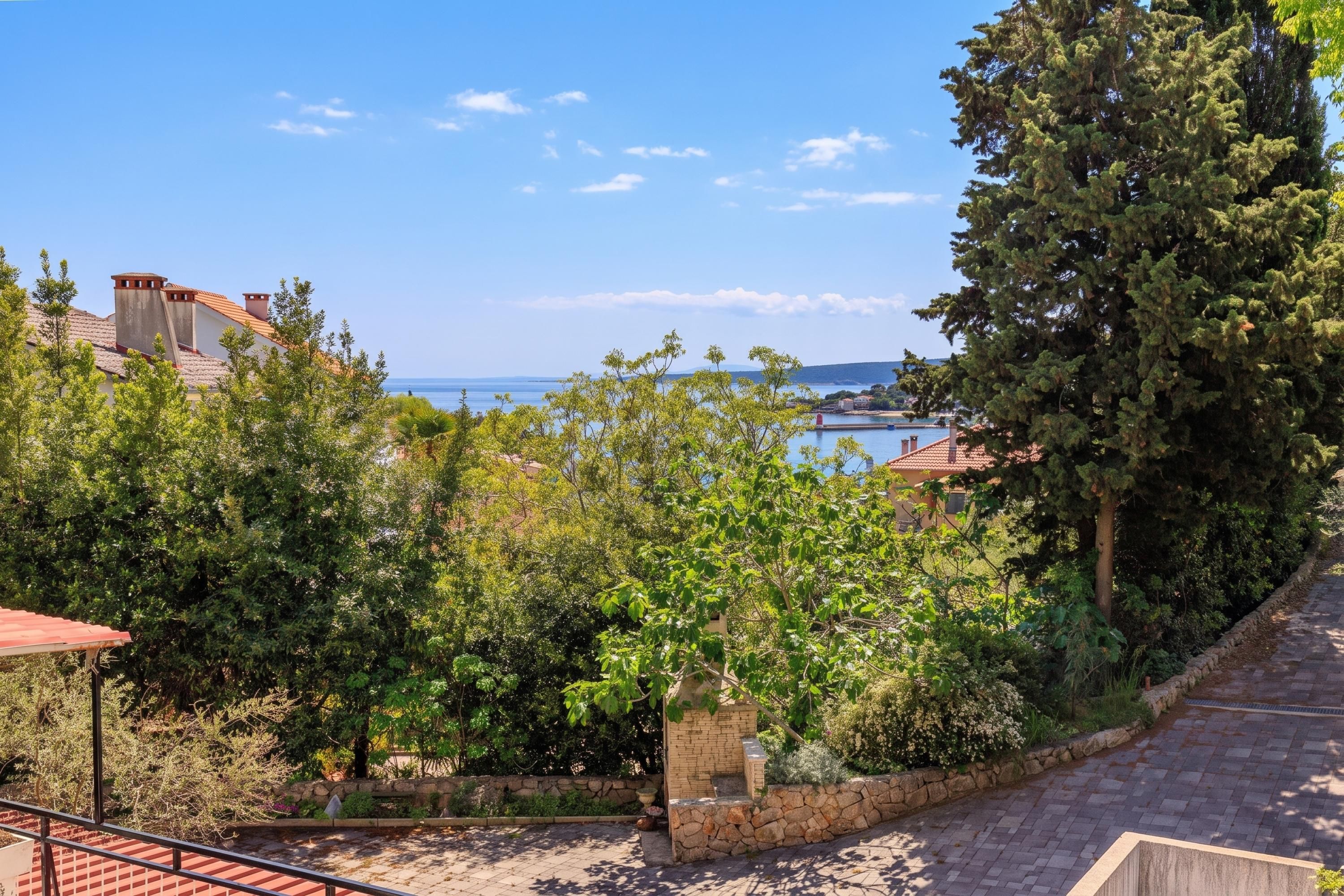 Une propriété située sur la côte, avec un chemin de pierre menant à une terrasse offrant une vue sur la mer.