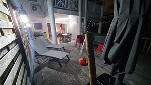 Ein überdachter Außenbereich mit Liegestühlen, einem Tisch und einer Hängematte.