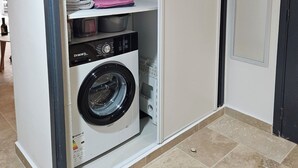 Ein kleiner Hauswirtschaftsraum mit Waschmaschine, Trockner und Regalen zur Aufbewahrung.