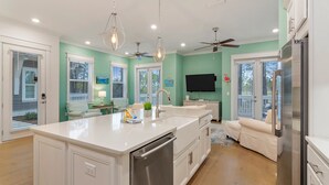 A modern kitchen with a central island, white cabinetry, stainless steel appliances, pendant lights, and a ceiling fan. - Bella Bonita by AvantStay | Pool, Peloton & Bikes, Golf Cart (Santa Rosa Beach)