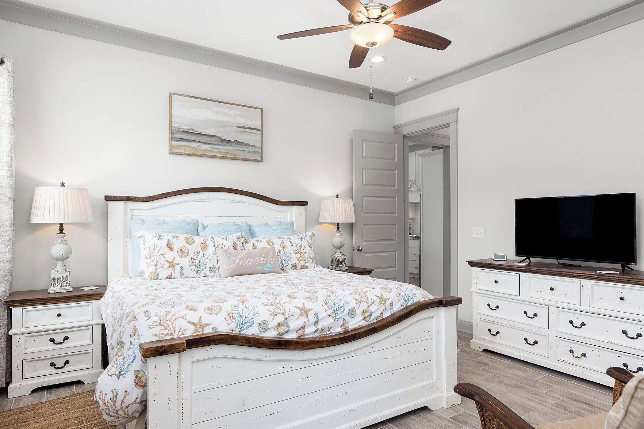 A bedroom with a bed, nightstands, a dresser, a television, and a ceiling fan.