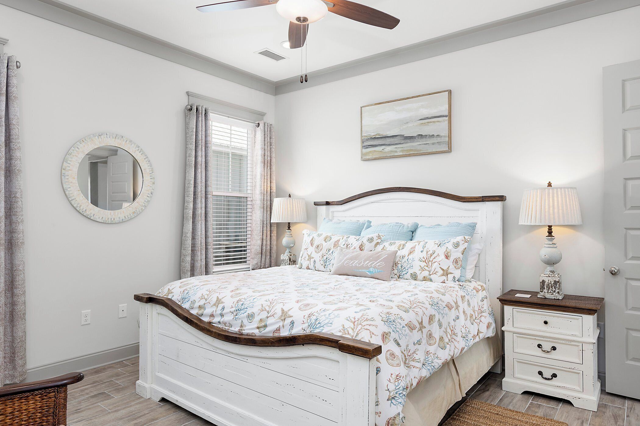 Une chambre à coucher avec un lit, des tables de chevet, un miroir et un ventilateur de plafond.