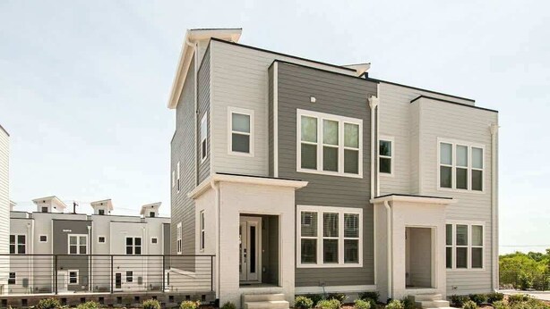 A modern multi-story residential building with a grey exterior, large windows, and a gated entrance.