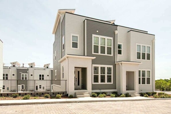 A modern multi-story residential building with a grey exterior, large windows, and a gated entrance. - Rooftop Creative Oasis – Close to Broadway (Nashville)